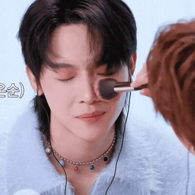 A Person Is Applying Makeup To Another Person 'S Face With A Brush GIF