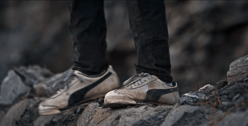 A Person Is Climbing Up A Rocky Hillside GIF
