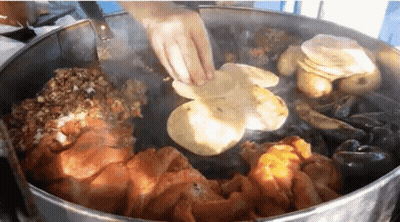 A Person Is Cooking A Bunch Of Food In A Large Pot GIF