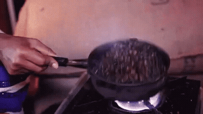 A Person Is Cooking Food In A Frying Pan On A Stove Top . GIF