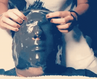 A Person Is Covering Their Face With A Black Mask GIF