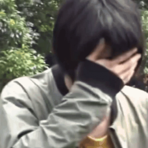 A Person Is Covering Their Face With Their Hand . GIF