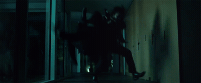 A Person Is Crawling Through A Dark Hallway In A Dark Room . GIF
