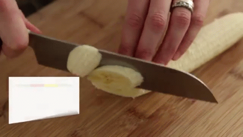 A Person Is Cutting A Banana With A Knife GIF