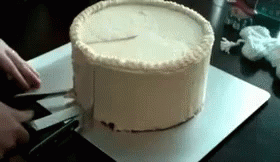 A Person Is Cutting A Cake With Scissors On A Cutting Board GIF
