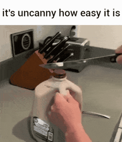 A Person Is Cutting A Gallon Of Milk With A Knife In A Kitchen . GIF
