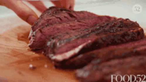 A Person Is Cutting A Large Piece Of Meat On A Cutting Board GIF