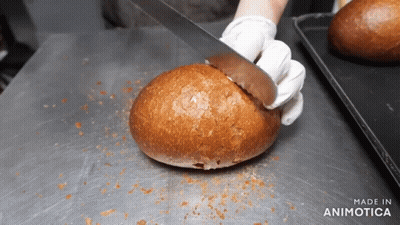 A Person Is Cutting A Loaf Of Bread With The Words Made In Animatica Visible GIF
