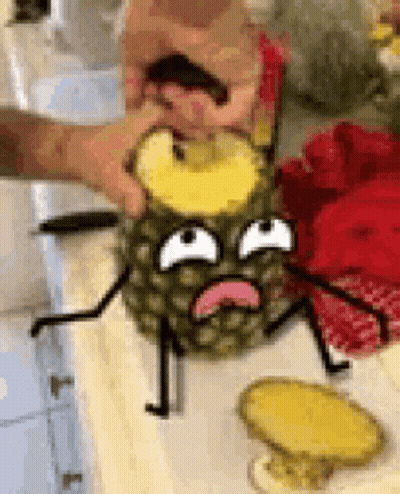 A Person Is Cutting A Pineapple With A Cartoon Face On It On A Table . GIF