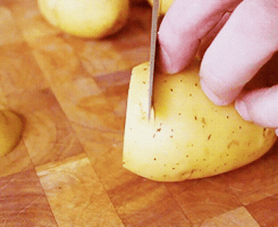 A Person Is Cutting A Potato With A Knife On A Cutting Board GIF