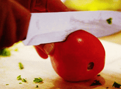 A Person Is Cutting A Tomato On A Cutting Board With A Knife That Has The Letter S On It GIF