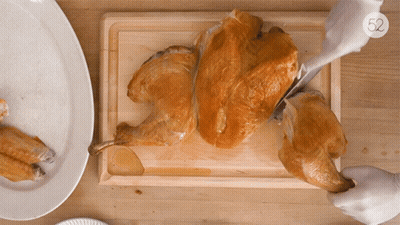 A Person Is Cutting A Turkey On A Cutting Board With The Number 52 On The Bottom Right GIF