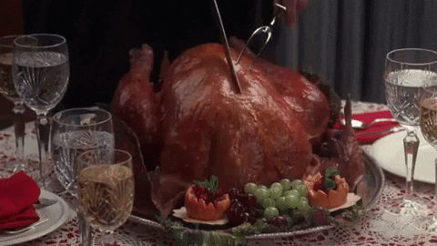 A Person Is Cutting A Turkey On A Table With Glasses Of Wine GIF