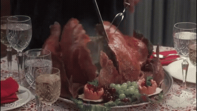 A Person Is Cutting A Turkey On A Table With Wine Glasses And Water GIF
