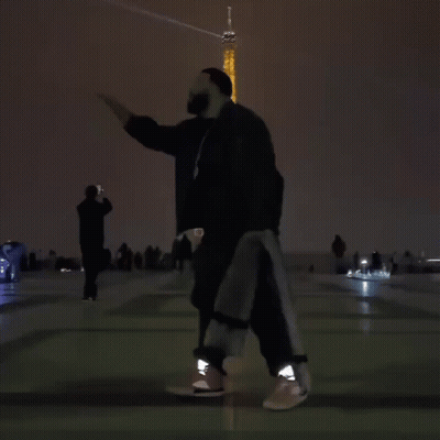 A Person Is Dancing In Front Of The Eiffel Tower At Night GIF