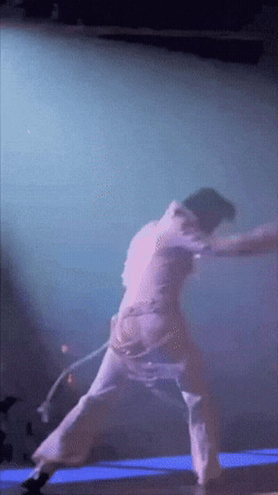 A Person Is Dancing On A Stage With A Purple Background GIF