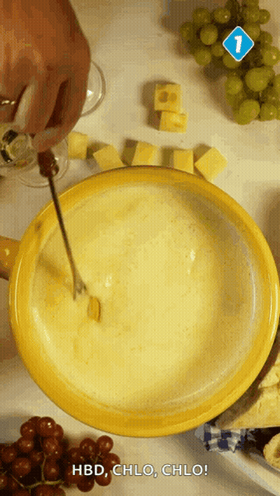 A Person Is Dipping A Piece Of Cheese Into A Bowl Of Fondue GIF