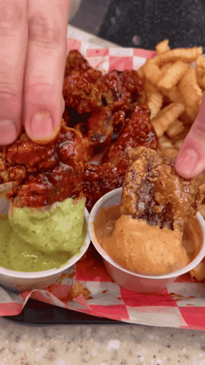 A Person Is Dipping A Piece Of Fried Chicken Into Guacamole Sauce GIF