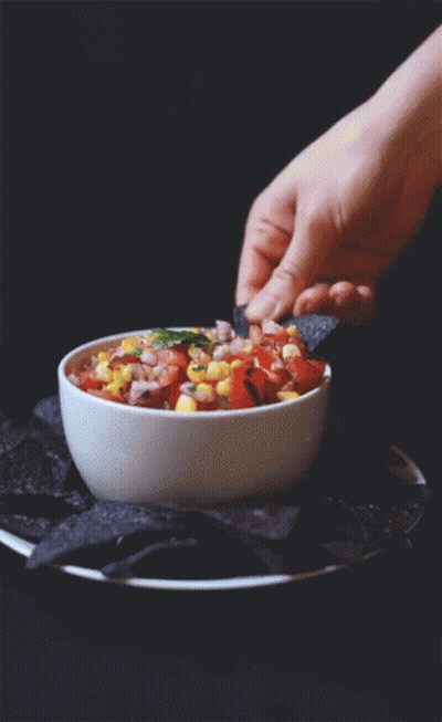 A Person Is Dipping A Tortilla Chip Into A Bowl Of Salsa GIF