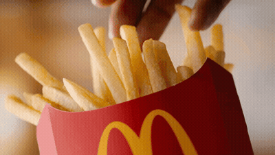 A Person Is Dipping French Fries Into A Red Mcdonald 'S Container GIF