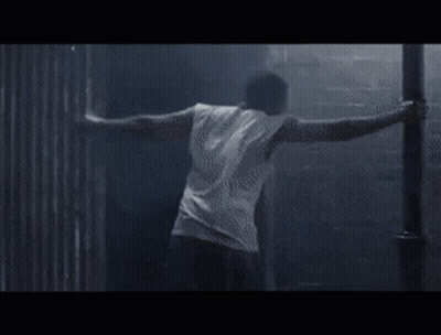 A Person Is Doing A Handstand In A Dark Room . GIF