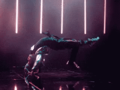 A Person Is Doing A Handstand In A Dark Room With Lights Behind Them GIF