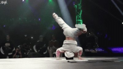A Person Is Doing A Handstand In Front Of A Crowd And The Word Strike Is On The Bottom Right GIF