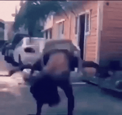 A Person Is Doing A Handstand On A Sidewalk In Front Of A Building . GIF