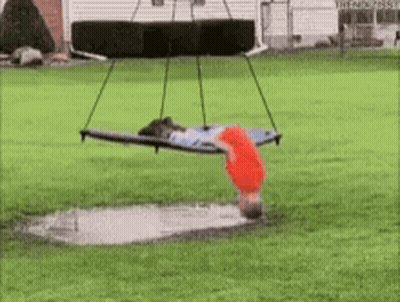 A Person Is Doing A Handstand On A Swing Over A Puddle Of Water . GIF