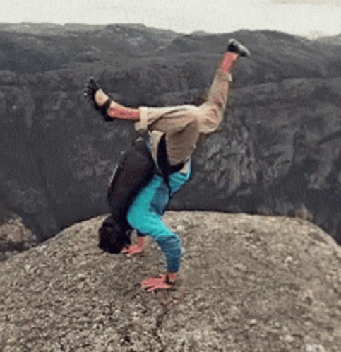 A Person Is Doing A Handstand On Top Of A Rocky Cliff GIF