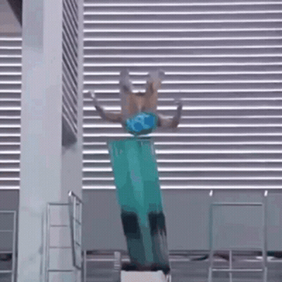 A Person Is Doing A Trick On A Diving Board In A Pool . GIF