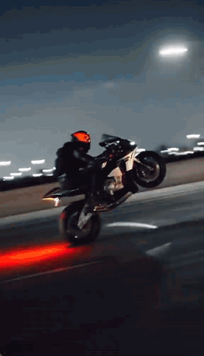 A Person Is Doing A Trick On A Motorcycle On A Highway At Night GIF