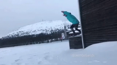 A Person Is Doing A Trick On A Snowboard In The Snow Near A Building . GIF