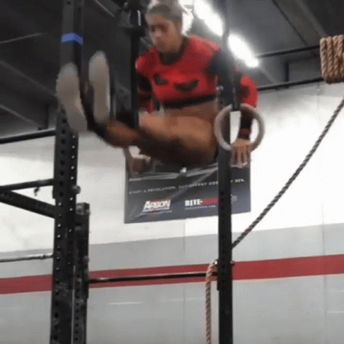 A Person Is Doing Exercises On Rings In Front Of A Banner That Says Aaron GIF