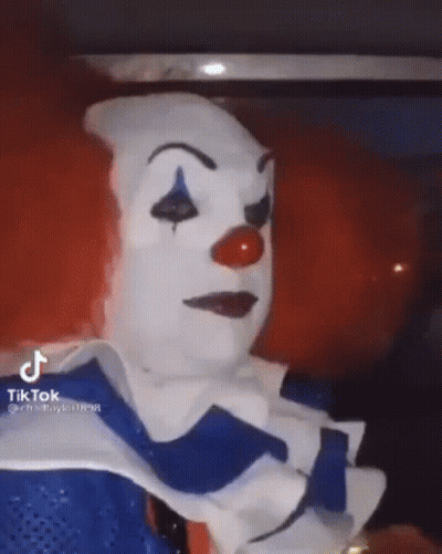 A Person Is Dressed As A Clown With A Red Nose And Blue Eyes . GIF