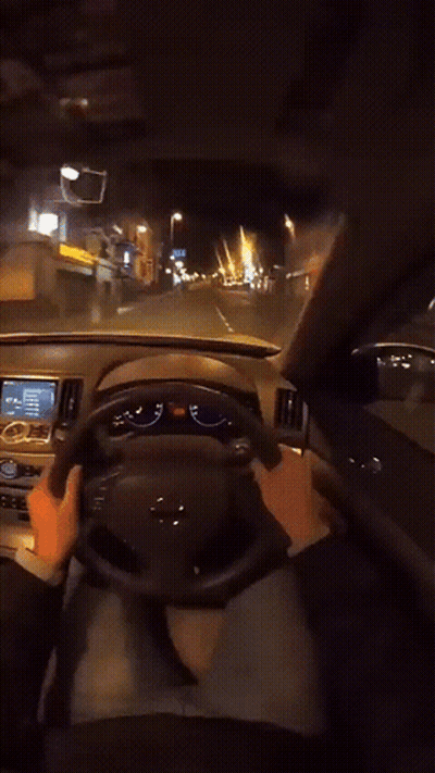 A Person Is Driving A Car At Night And Their Hands Are On The Steering Wheel And The Dashboard GIF