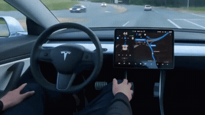 A Person Is Driving A Tesla Model 3 With The Time Of 4:44 GIF