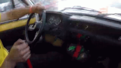 A Person Is Driving A Yellow Car And Holding The Steering Wheel GIF