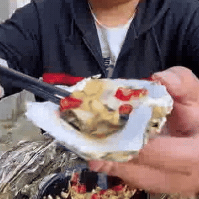 A Person Is Eating Oysters With Chopsticks And A Spoon . GIF