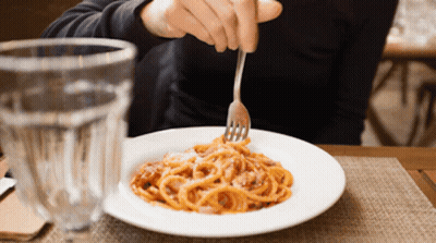 A Person Is Eating Spaghetti With A Fork In Front Of A Glass GIF