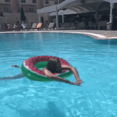A Person Is Floating On A Watermelon Shaped Float In A Swimming Pool GIF