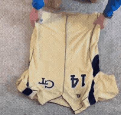 A Person Is Folding A Yellow Jersey With The Number 14 On It GIF