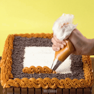 A Person Is Frosting A Cake With Mr.cakes Written In The Corner GIF