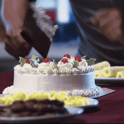 A Person Is Frosting A Cake With Whipped Cream And Cherry Decorations GIF