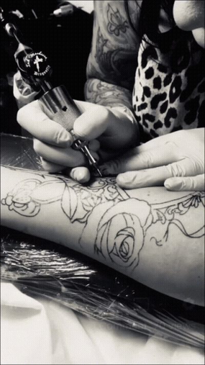 A Person Is Getting A Tattoo On Their Arm With A Machine That Has A Cross On The Top GIF