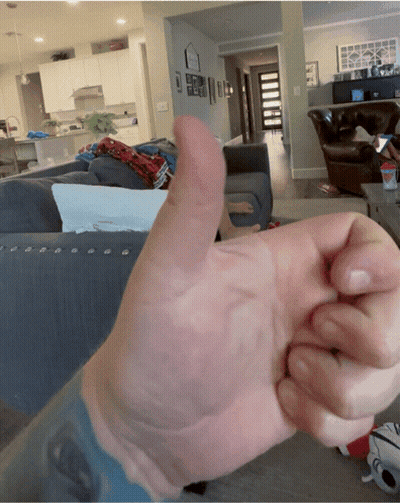 A Person Is Giving A Thumbs Up In Front Of A Living Room GIF