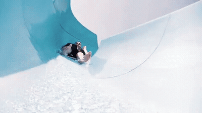A Person Is Going Down A Water Slide In A Pool GIF