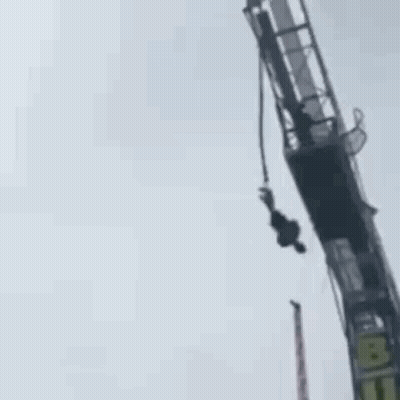 A Person Is Hanging Upside Down From A Bungee Tower . GIF