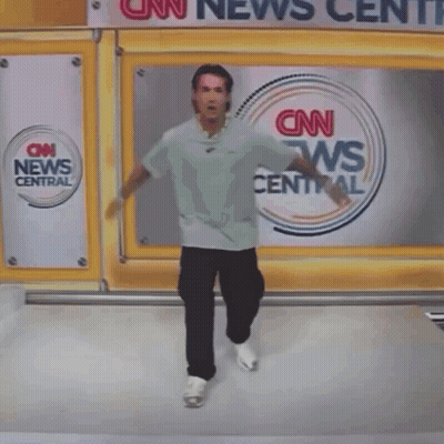 A Person Is Hanging Upside Down In Front Of A Cnn News Center Sign GIF
