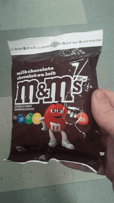 A Person Is Holding A Bag Of M & M 'S Milk Chocolate GIF